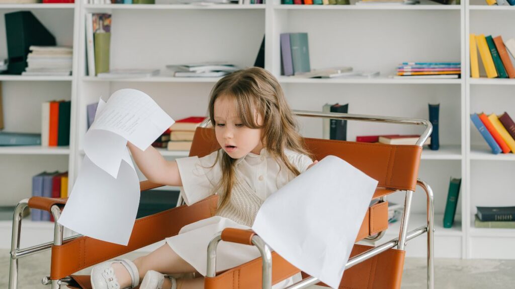 A young girl in an office setting scatters autism research papers