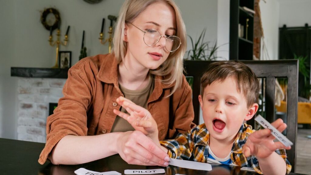 A mother works with her son using flashcards at the kitchen table